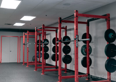 A gym with many red racks and some black plates