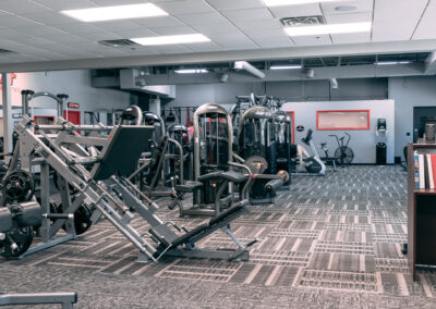 A gym with many machines and people in it