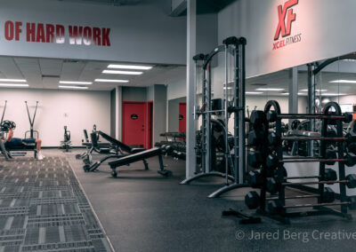 A gym with many different machines and a red door.