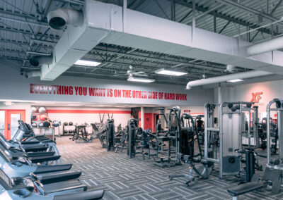 A gym with many machines and people in it