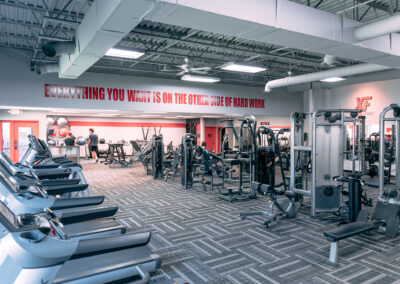 A gym with many machines and people in it