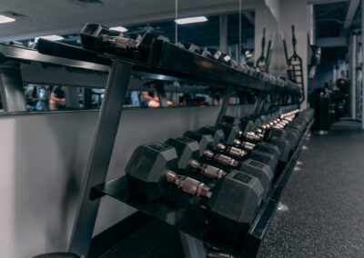 A row of dumbbells in a gym with people watching.