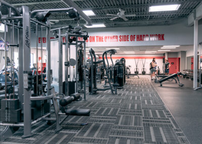 A gym with many machines and people in it